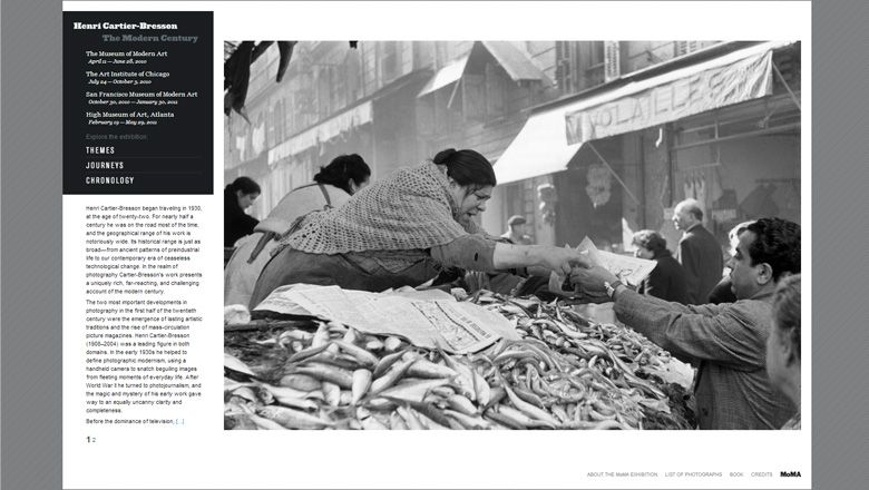 Screenshot of a website showing a large black and white photograph. Woman hands fish to a customer on a fish market.